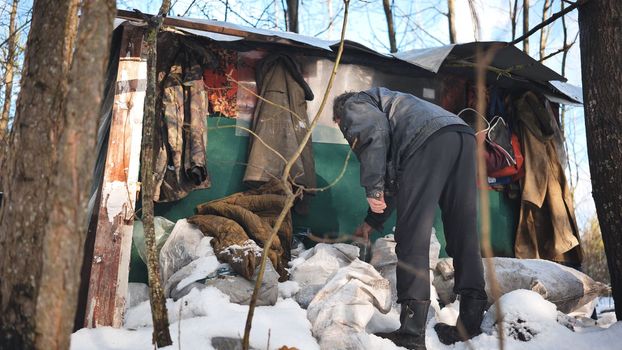 A homeless man goes through things at his cabin in the woods in winter