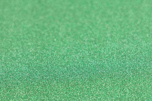 Green shiny glitter paper texture. Shining luxurious fabric. Glimmering golden christmas background paper texture. Shining luxurious fabric. Glimmering light green color st Patric, christmas background.