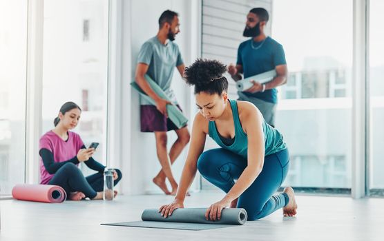 Yoga, fitness and a black woman rolling her mat on the floor of a studio for exercise or wellness. Gym, workout and health with a female yogi in the gym for pilates training or spiritual wellbeing.