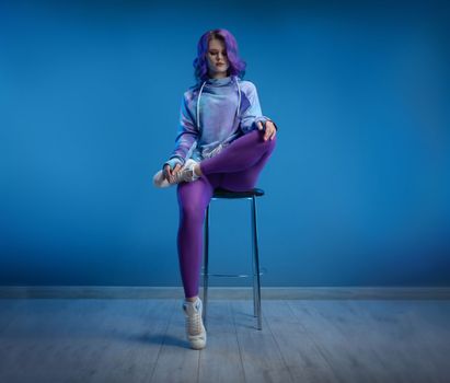 Sexy girl in stylish bright youth sportswear and purple hair sexy poses on a bright background copypast