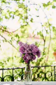 Bouquet of lilacs stands in a bottle on the table on the balcony. High quality photo