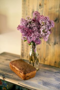 Bouquet of lilac stands with homemade rye yeast-free bread on the table. High quality photo