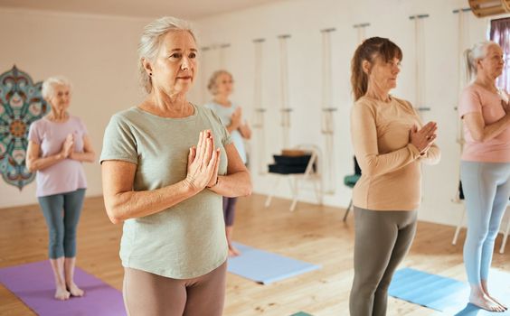 Yoga, meditation and fitness with a senior woman in an exercise class for holistic wellness or mental health. Gym, zen and meditate with a mature female yogi in a studio for inner peace or balance.