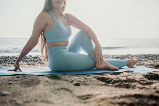 Middle aged well looking woman with black hair doing Pilates with the ring on the yoga mat near the sea on the pebble beach. Female fitness yoga concept. Healthy lifestyle, harmony and meditation.