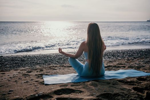 Middle aged well looking woman with black hair doing Pilates with the ring on the yoga mat near the sea on the pebble beach. Female fitness yoga concept. Healthy lifestyle, harmony and meditation.
