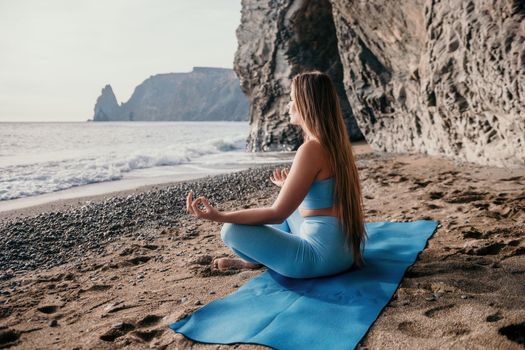 Middle aged well looking woman with black hair doing Pilates with the ring on the yoga mat near the sea on the pebble beach. Female fitness yoga concept. Healthy lifestyle, harmony and meditation.