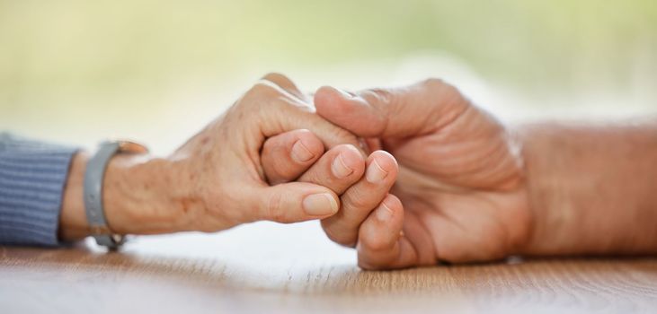 Elderly couple, holding hands and support for comfort, love or help on table for compassion, pain or sympathy. Senior man, old woman and helping hand with empathy, trust and care in home for bonding.