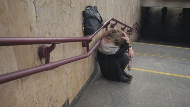 A young girl crying by the stairs in the subway