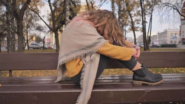 A young girl crying on a park bench in the fall