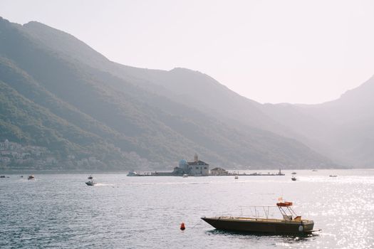 Boat is moored in the bay against the backdrop of the island of Gospa od Skrpjela. Montenegro. High quality photo