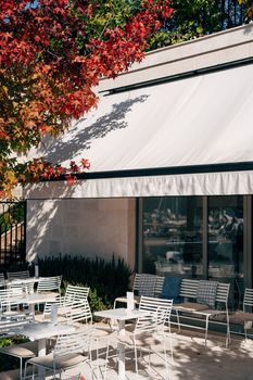 Tables and chairs are on the tiles outside the restaurant. Porto. Montenegro. High quality photo