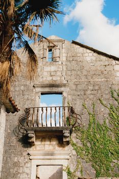 Old stone wall of a ruined building with a balcony, overgrown with ivy. High quality photo