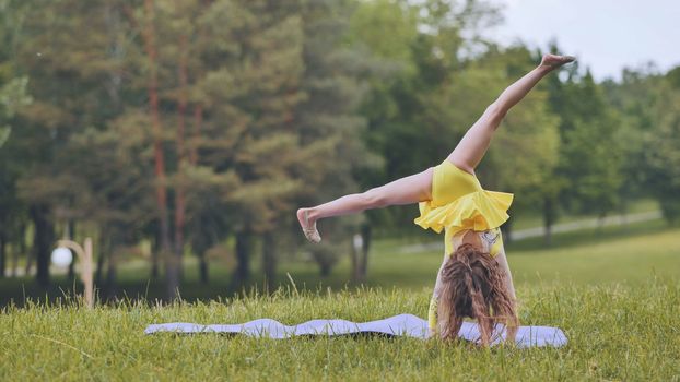 A little girl performs the elements of rhythmic gymnastics in the park