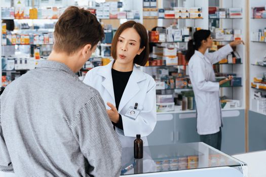 Professional pharmacist advise or explain property of qualified medical product to customer in pharmacy, druggist answer to client healthcare inquiry, medical service and consultation concept.