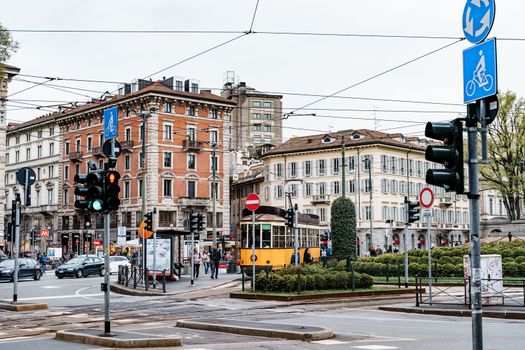 Yellow tram travels down the street against the backdrop of ancient buildings. Milan, Italy. High quality photo