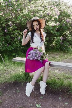 A fashionable girl with dark hair, a spring portrait in lilac tones in summer. Bright professional makeup