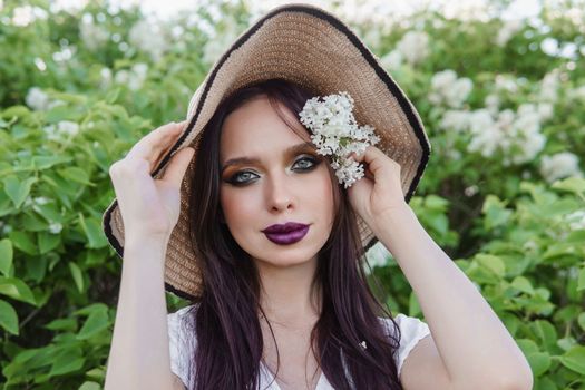 A fashionable girl with dark hair, a spring portrait in lilac tones in summer. Bright professional makeup