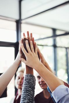 Heres to teamwork. a group of people high-fiving in the office