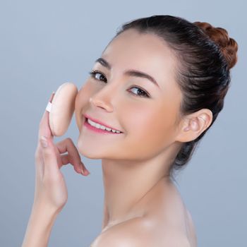 Glamorous beautiful female model applying cushion powder for facial makeup concept. Portrait of flawless perfect cosmetic skin woman put powder puff on her face in isolated background.
