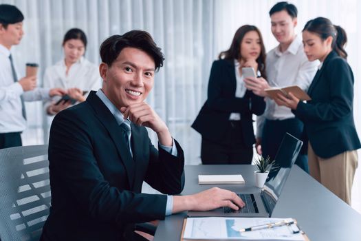 Portrait of focus young successful confident male manager, executive wearing business wear in harmony office arm crossed with blurred meeting background of colleagues, office worker.