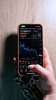 POV Spot trading cryptocurrency bitcoin on the phone during the fall of the market. Top view, vertical