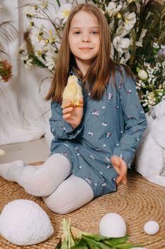 Two girls in a beautiful Easter photo zone with flowers, eggs, chickens and Easter bunnies. Happy Easter holiday