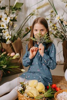 Two girls in a beautiful Easter photo zone with flowers, eggs, chickens and Easter bunnies. Happy Easter holiday