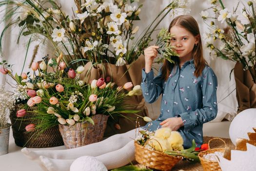Two girls in a beautiful Easter photo zone with flowers, eggs, chickens and Easter bunnies. Happy Easter holiday