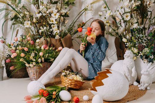Two girls in a beautiful Easter photo zone with flowers, eggs, chickens and Easter bunnies. Happy Easter holiday