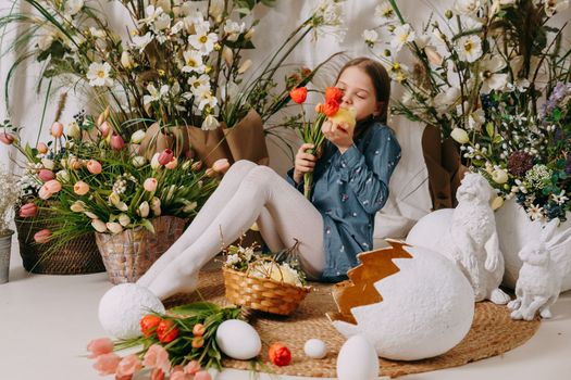 Two girls in a beautiful Easter photo zone with flowers, eggs, chickens and Easter bunnies. Happy Easter holiday