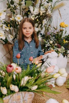 Two girls in a beautiful Easter photo zone with flowers, eggs, chickens and Easter bunnies. Happy Easter holiday