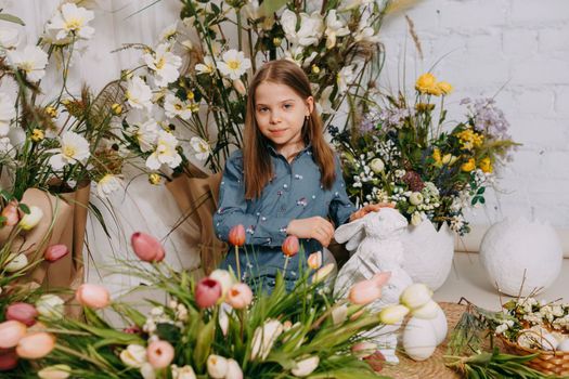 Two girls in a beautiful Easter photo zone with flowers, eggs, chickens and Easter bunnies. Happy Easter holiday