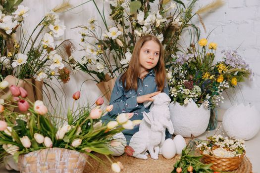 Two girls in a beautiful Easter photo zone with flowers, eggs, chickens and Easter bunnies. Happy Easter holiday