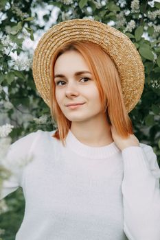 Portrait of a woman in a straw hat in a cherry blossom. Free outdoor recreation, spring blooming garden