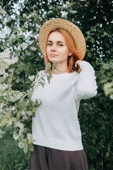 Portrait of a woman in a straw hat in a cherry blossom. Free outdoor recreation, spring blooming garden