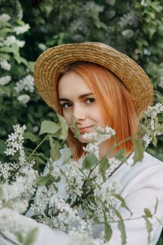 Portrait of a woman in a straw hat in a cherry blossom. Free outdoor recreation, spring blooming garden