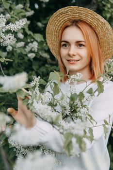 Portrait of a woman in a straw hat in a cherry blossom. Free outdoor recreation, spring blooming garden