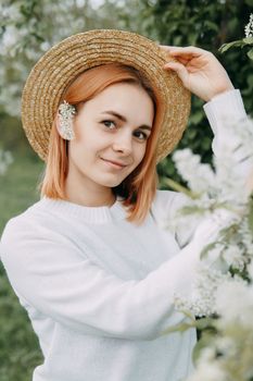 Portrait of a woman in a straw hat in a cherry blossom. Free outdoor recreation, spring blooming garden