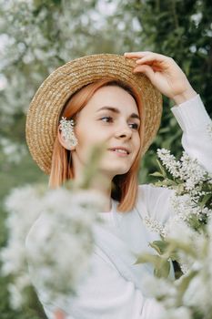 Portrait of a woman in a straw hat in a cherry blossom. Free outdoor recreation, spring blooming garden