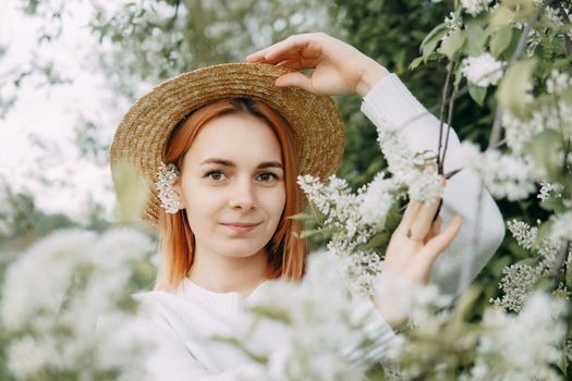 Portrait of a woman in a straw hat in a cherry blossom. Free outdoor recreation, spring blooming garden