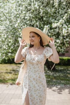 An attractive long-haired woman walks in the spring in the park of blooming apple trees. Spring portrait of a woman