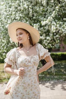 An attractive long-haired woman walks in the spring in the park of blooming apple trees. Spring portrait of a woman