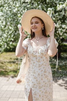 An attractive long-haired woman walks in the spring in the park of blooming apple trees. Spring portrait of a woman