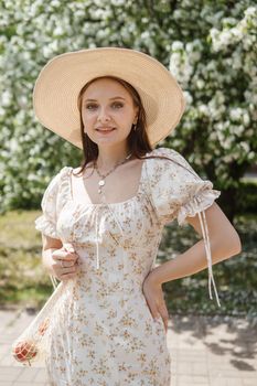 An attractive long-haired woman walks in the spring in the park of blooming apple trees. Spring portrait of a woman