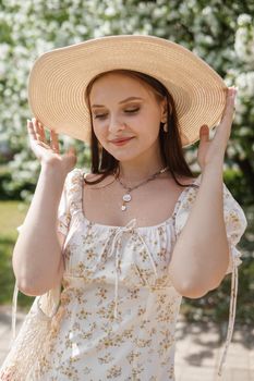 An attractive long-haired woman walks in the spring in the park of blooming apple trees. Spring portrait of a woman