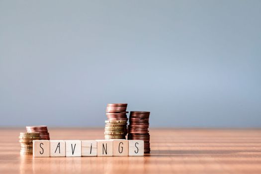 Stacking coins pile wooden box with text word savings for planning step up to growing, Saving money for retirement fund and the future plan concept. copy space succes