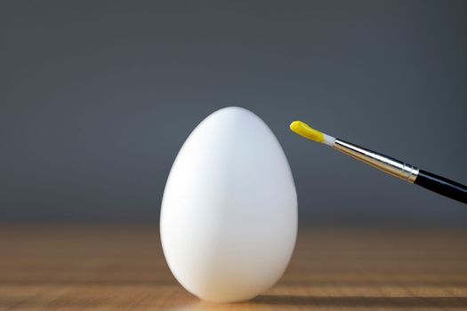 rough brush is painting a fragile easter egg with Yellow color, prepering for Holiday Happy Easter concept closeup colorful hobby
