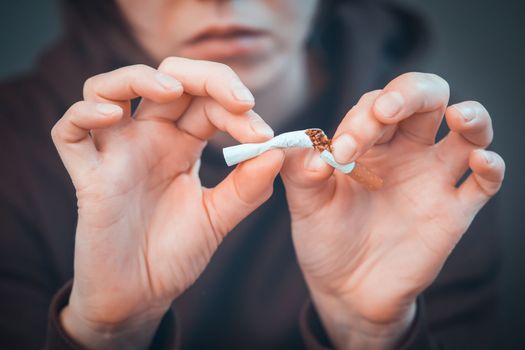 Young girl decisively breaks a cigarette in her hands, close-up view, a woman gets rid of nicotine addiction and chooses a healthy lifestyle, takes care of her beauty and health.