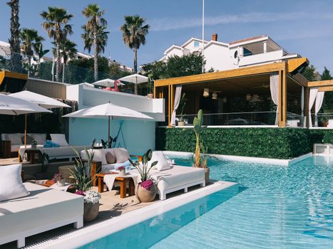 Flowers in flowerpots near double sun loungers by the pool. High quality photo