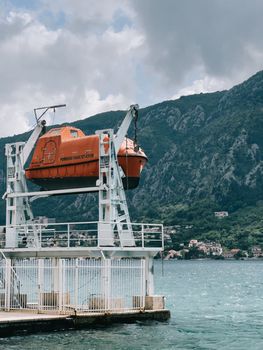 Rescue ship hangs on chains on a port davit above the pier. High quality photo